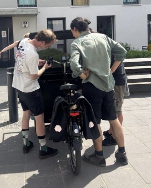 Drei Menschen stehen vor einem Fahrrad. Es wird erklärt, wie der Bordcomputer zu bedienen ist.