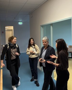 Vier Frauen stehen zueinander gewandt in einem Flur. Die Frau rechts erklärt gerade etwas