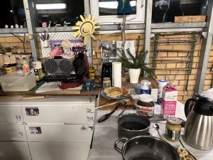 Eine Küchenzeile. Darauf steht u.a. ein Kaffeekann,e, milch, Nutella, ein Waffeleisen, Waffeln