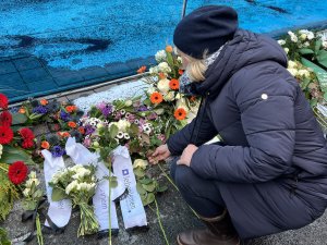 Eine Frau legt eine weisse Rose nieder