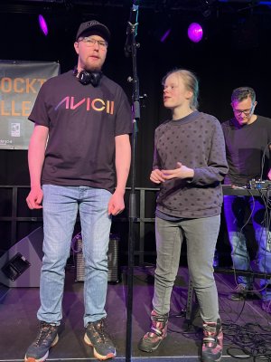 Ein Mann und eine Frau stehen auf einer B&uuml;hne vor einem Mikrophon und sinhgen