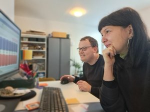 Ein Mann und eine Frau sitzen vor einem Computer und schauen auf den Monitor