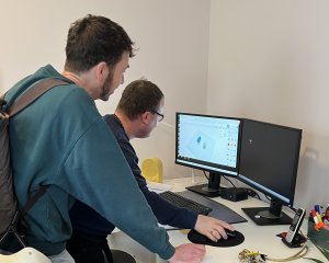 zwei M&auml;nner gucken auf den Bildschirm eines Computers