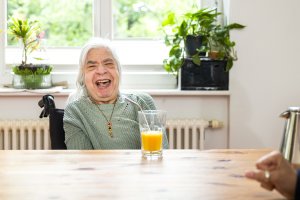 Eine Frau sitzt an einem Tisch und lacht.
